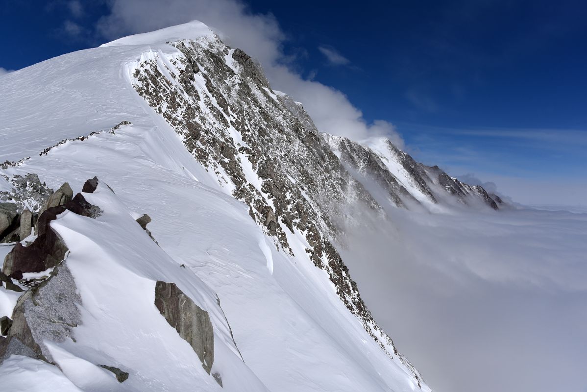 11B The Steep Cliff Of Branscomb Peak And Principe de Asturias Peak With Clouds Below From Mount Vinson High Camp